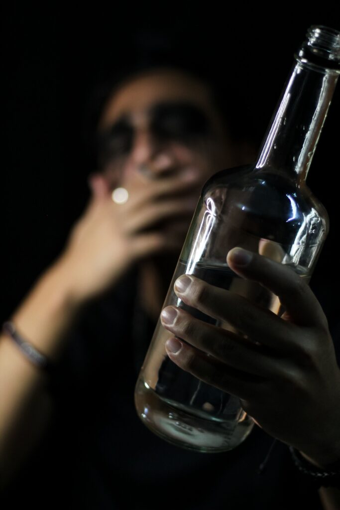 An artistic photo highlighting a man with a bottle, focused on reflection and mood.